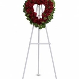 Heart-shaped red rose wreath on a white easel