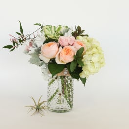 Bouquet of peach roses and pale hydrangeas in a glass vase
