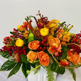 Orange and yellow floral arrangement in a white vase