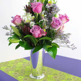 Pink roses and lilies arranged in a tall glass vase