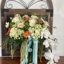 Bouquet of white orchids, roses, and hydrangeas in a glass vase with ribbons