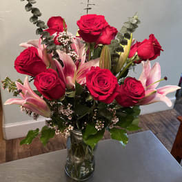 Red roses and pink lilies arranged in a clear glass vase.