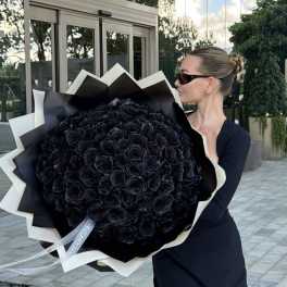 Woman holding a large bouquet of black roses wrapped in black and white paper