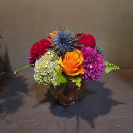Colorful mixed flower arrangement in a round glass vase
