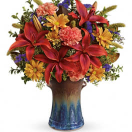 Red lilies and yellow daisies in a blue ceramic vase