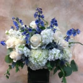 White roses and hydrangeas with blue flowers in a black vase