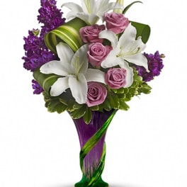 Bouquet of white lilies, pink roses, and purple flowers in a purple vase