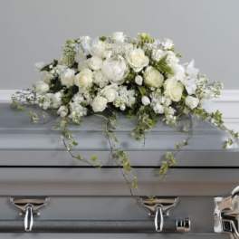 White floral casket spray with trailing greenery