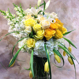 Yellow and white roses with lilies in a glass vase