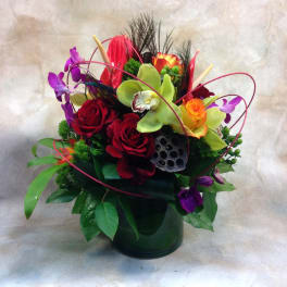 Colorful bouquet of roses and orchids in a dark vase
