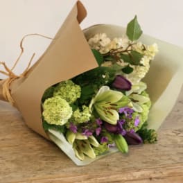 Bouquet of lilies, hydrangeas, and purple flowers wrapped in brown paper
