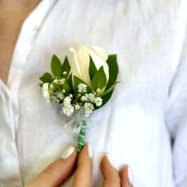 White rose boutonniere with baby's breath and green leaves