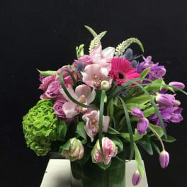 Mixed pink and purple floral arrangement in a glass vase