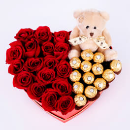 Heart-shaped box of red roses with a teddy bear and chocolates