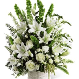 White lilies and roses in a white basket arrangement