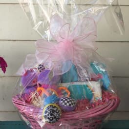 Pink gift basket wrapped in clear cellophane with assorted items inside