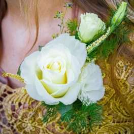 White rose corsage with green accents on a wrist