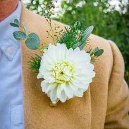 White flower boutonniere pinned to a tan jacket