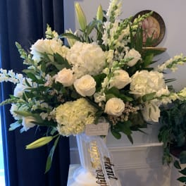 Large white floral arrangement in a pedestal vase