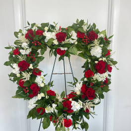 Heart-shaped wreath of red and white flowers on a stand