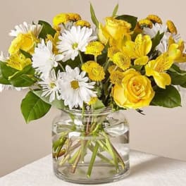 Yellow roses and white daisies in a clear glass vase