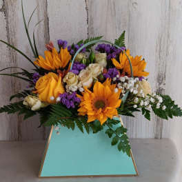 Bouquet of orange sunflowers, cream roses, and purple filler in a turquoise box