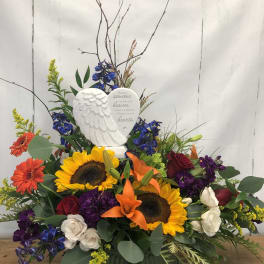 Sympathy arrangement with sunflowers, roses, and an angel plaque