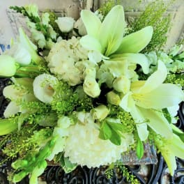 White lilies and roses arranged with hydrangeas and greenery