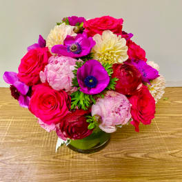 Bright mixed bouquet of pink, red, and cream flowers in a glass vase