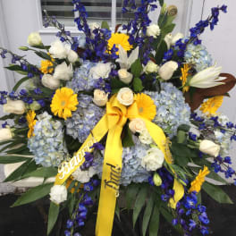 Large floral spray with blue, white, and yellow flowers and yellow ribbons