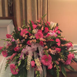 Pink and white floral casket spray with ribbon streamers