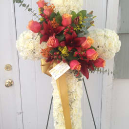 Cross-shaped floral spray with white flowers, red roses, and a gold ribbon