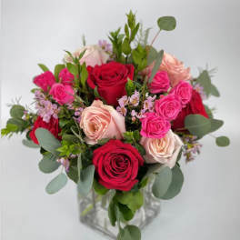 Bouquet of red, pink, and blush roses in a clear glass vase
