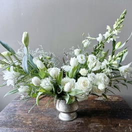 White floral arrangement in a silver vase with roses and tulips