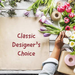 Tulips and wrapping supplies around a paper sign reading Classic Designer's Choice