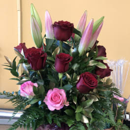 Bouquet of red and pink roses with unopened lilies in a vase