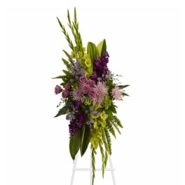Tall floral spray with purple and green flowers on a white easel