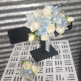 White rose bouquet with pale blue accents and ribbon on a black stand
