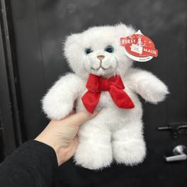 White teddy bear with a red bow being held in one hand