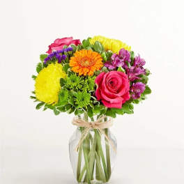 Mixed bouquet of bright flowers in a clear glass vase