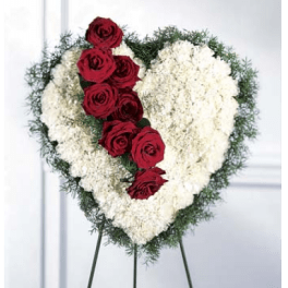 Heart-shaped floral tribute with red roses and white flowers on an easel