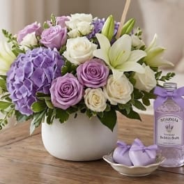 Lavender and white roses with hydrangeas and lilies in a white vase
