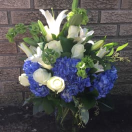 Blue hydrangeas and white lilies in a glass vase