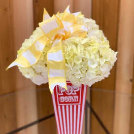 White hydrangea arrangement in a popcorn container with a yellow ribbon