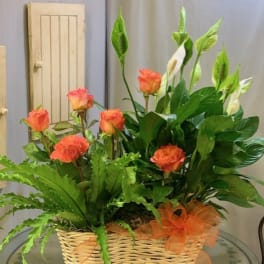 Orange roses and white calla lilies in a wicker basket