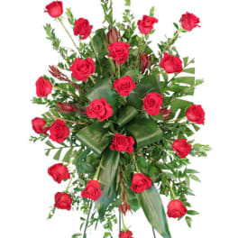 Tall standing spray of red roses with structured green leaves on a metal easel.