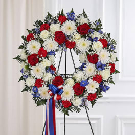 Red, white, and blue floral wreath on a black easel with ribbon