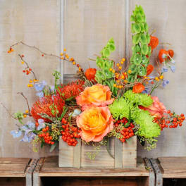 Wooden box arrangement with orange roses, green mums, and berries