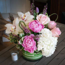 Pink and white floral arrangement in a green striped vase