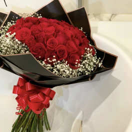 Bouquet of red roses with white baby's breath in black wrap